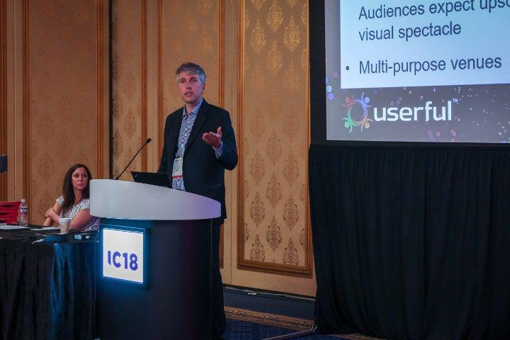Userful的首席技术官Tim Griffin在2018年Infocomm大会上做关于AV-over-IP的演讲，背景是Matrix Video Communications的Marielle Crisanti。