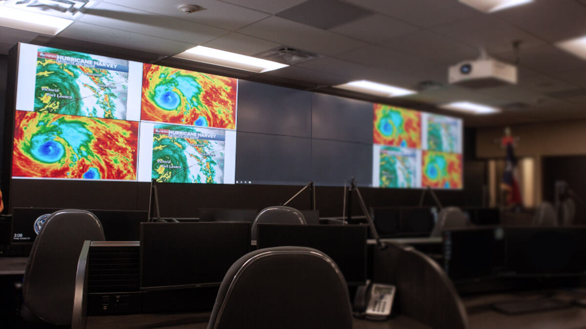 空旷的控制室里有显示在大型电视墙上的天气雷达，以及工作站