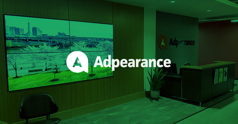 空旷的Adpearance大厅，坐席后面有Userful供电的视频墙，显示摄影作品，接待台后面的墙上有Adpearance的标志，上面有绿色的覆盖物和标志。