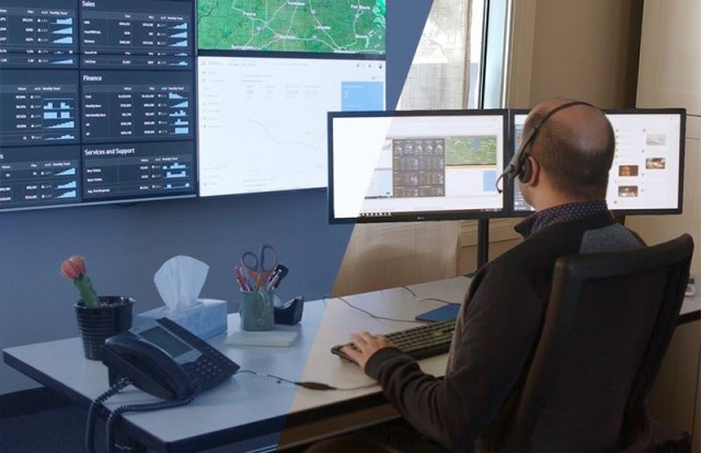 控制室里的员工在工作台上打字，看着显示数据仪表板和地图的视频墙