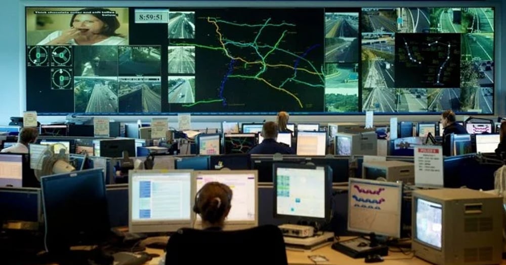 应急操作中心，有视频墙显示实时交通摄像头和路线，员工在工作站工作