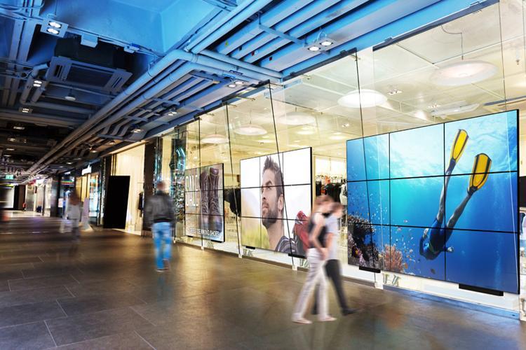 在商场的走廊上有多面大型用户视频墙，展示广告和艺术。