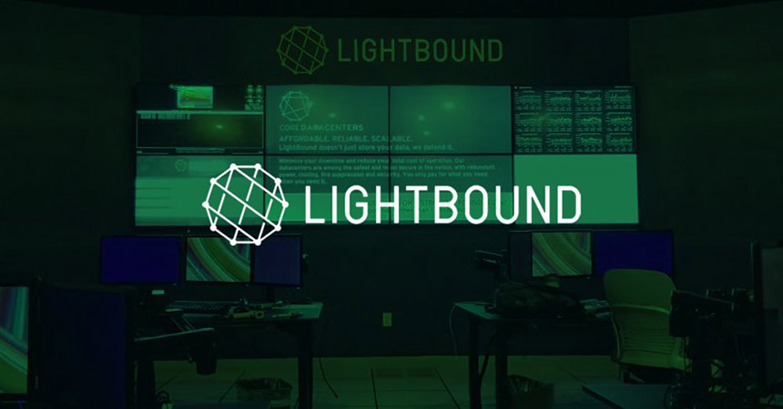 空旷的Lightbound控制室，有2个工作站和显示网站、数据和广告的视频墙，上面有绿色覆盖物和标志。
