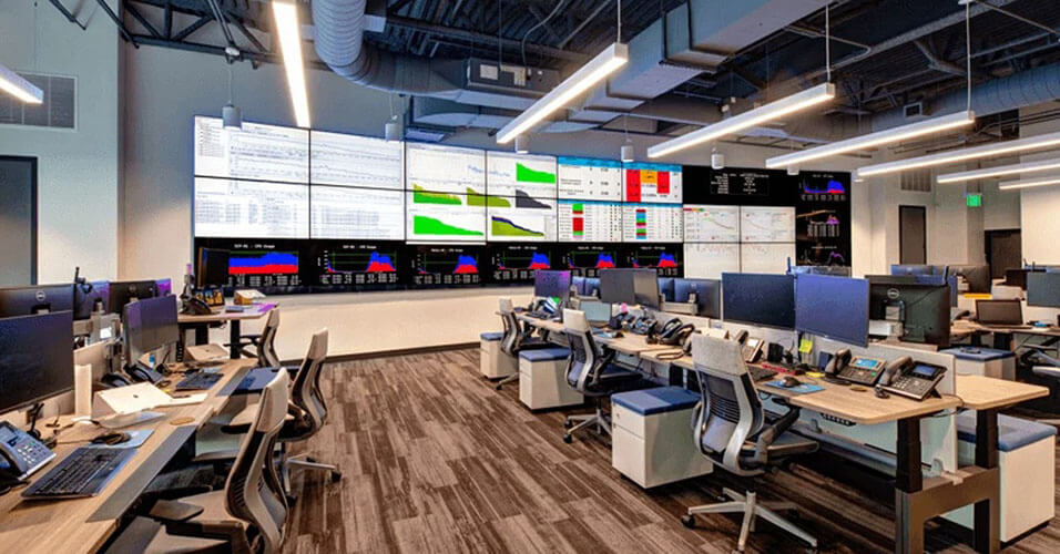 空旷的SpectrumVoIP网络运营中心有许多工作站和一个较大的视频墙显示数据仪表板